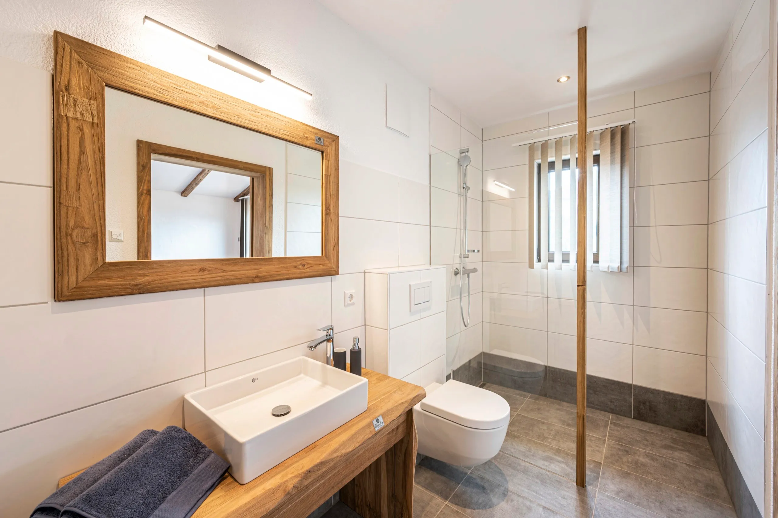 Badezimmer mit Holzspiegel, Aufsatzwaschbecken und Dusche