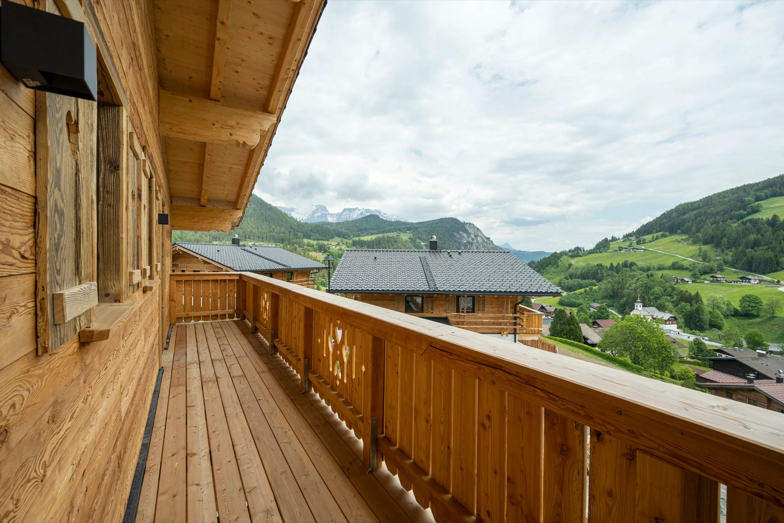 Holzbalkon eines Chalets mit Blick über das Tal auf das Dachsteinmassiv