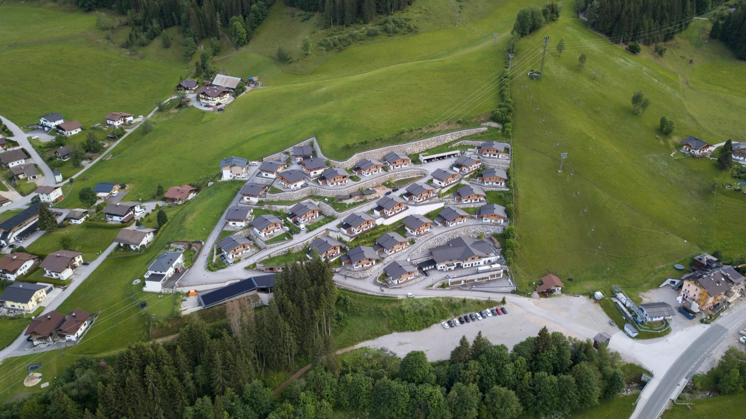 Luftbild des Chaletdorfs zwischen Wiesen und Wald