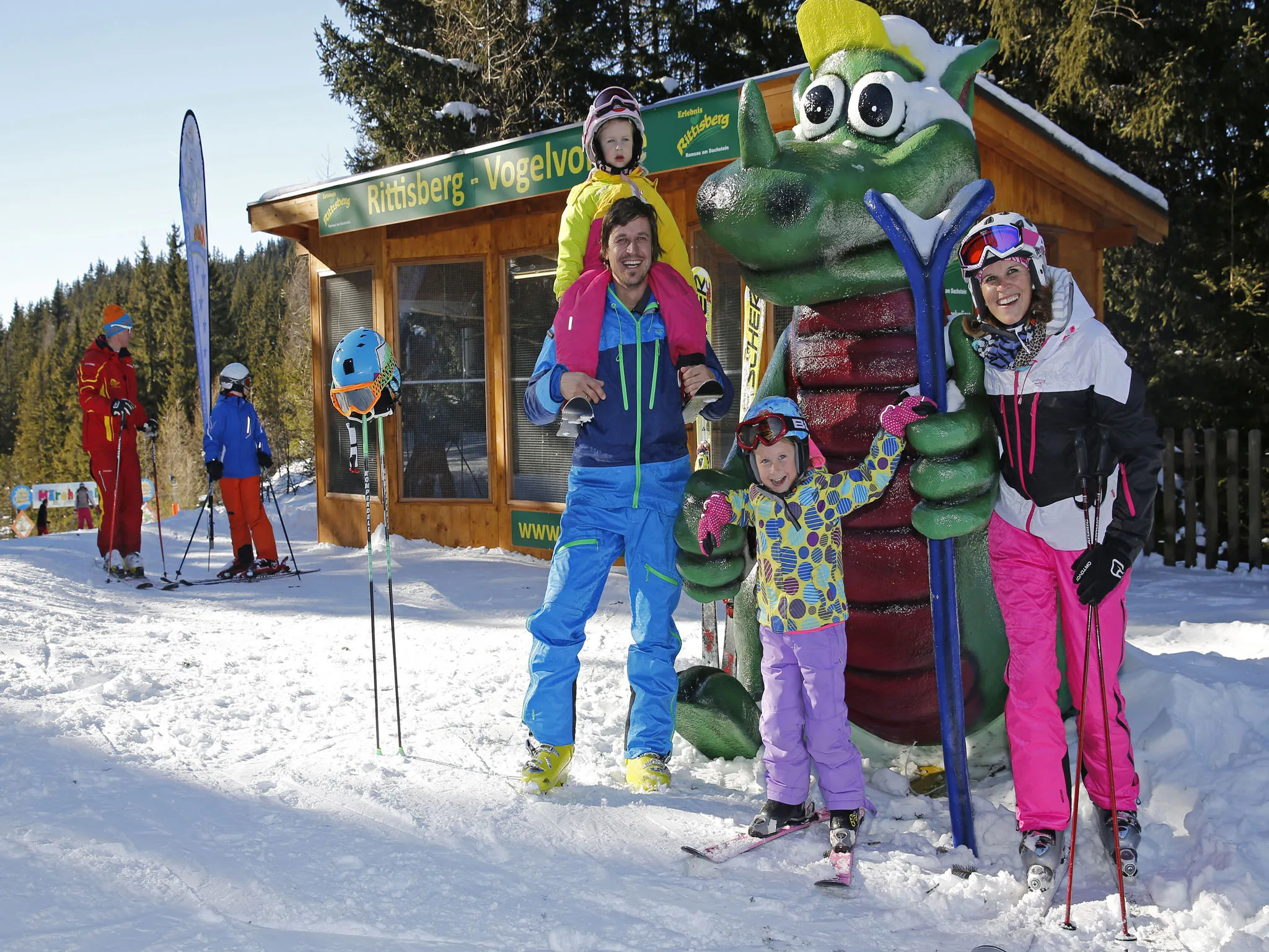 Familie in Skikleidung vor einer Hütte im Schnee